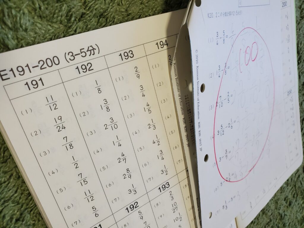 公文数学E教材191〜200番のプリントと、分数計算の答えが書かれた学習ページの写真