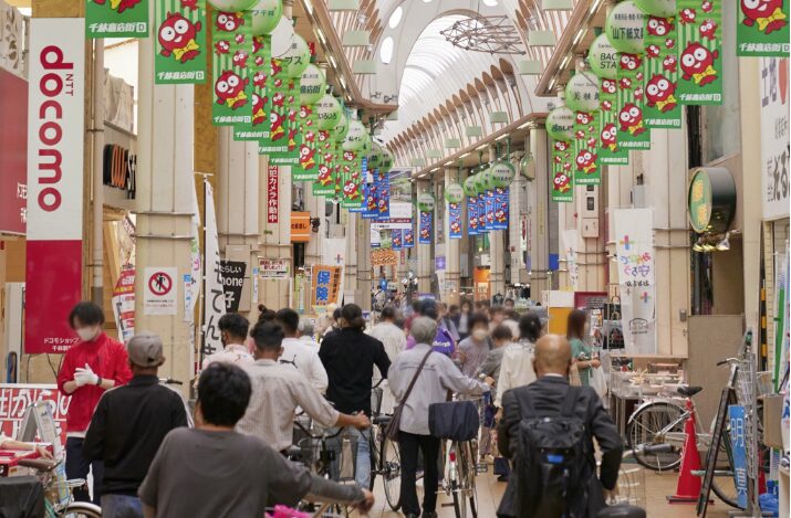 商店街を歩く人々の様子。にぎやかなアーケード内で多くの人が行き交う風景