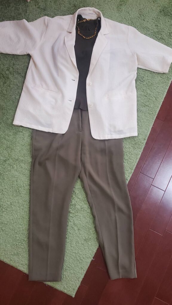 ベージュのジャケットに黒トップスとカーキのテーパードパンツを合わせたきれいめコーディネート